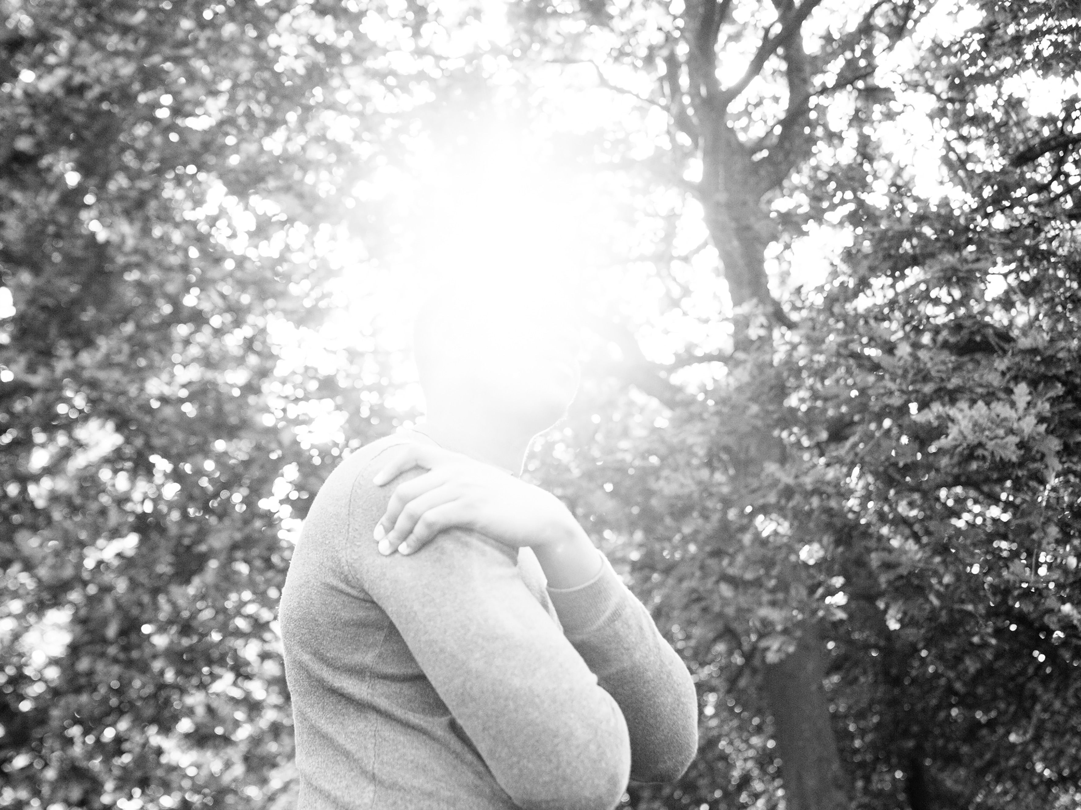 A black and white photograph showing a person in sunlight in the park